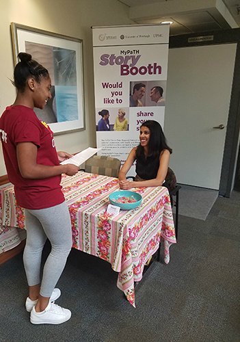 A potential participant talks with a Story Booth team member